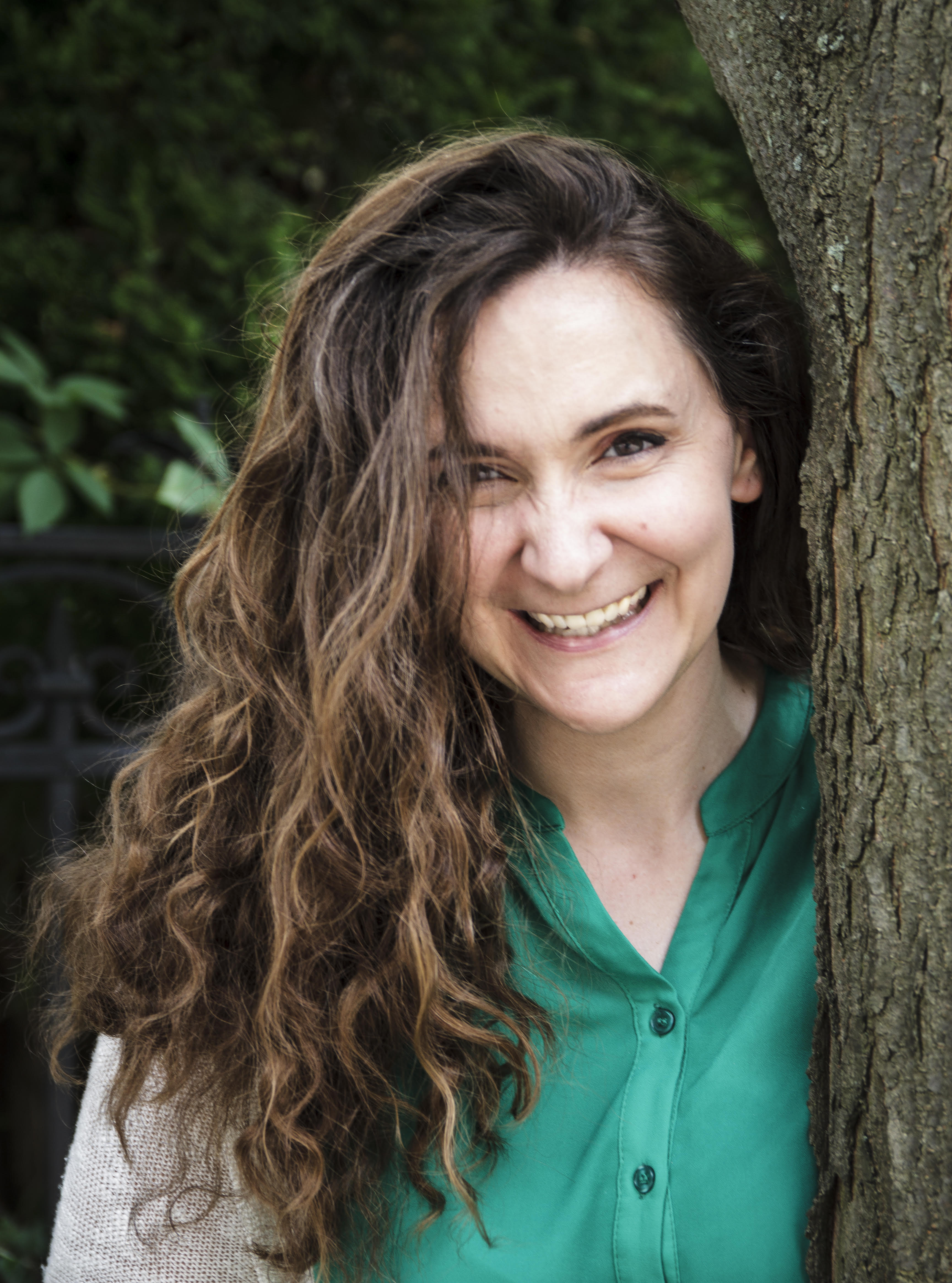 Amanda Leduc smiling at the camera. She is wearing a green button-down shirt and has long wavy hair