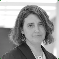 A black and white head shot of Kate Davis, standing in an office space